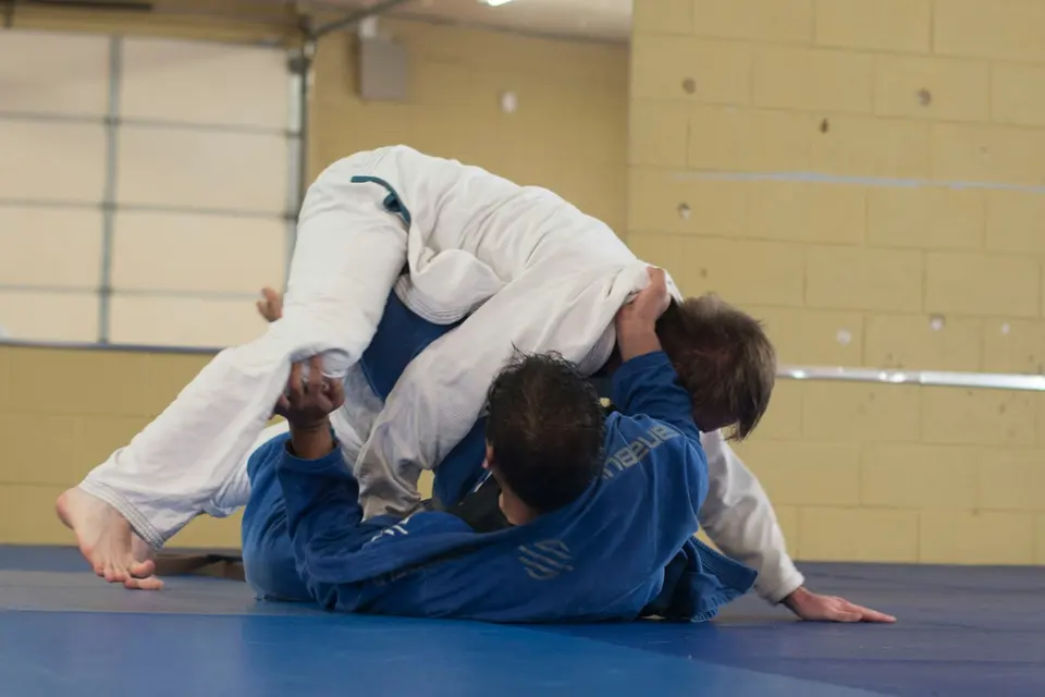 Dois atletas de kimono treinando jiu-jitsu no tatame